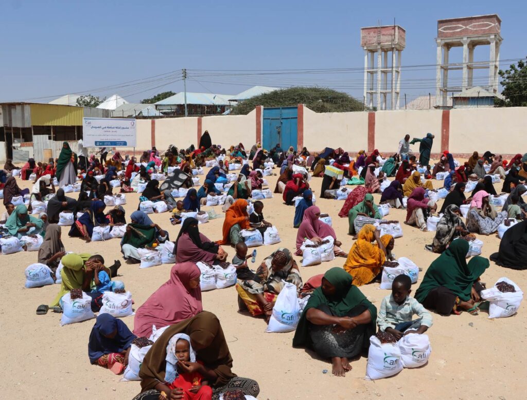 Mothers and children with nutrition assistance supplies at a displacement camp.